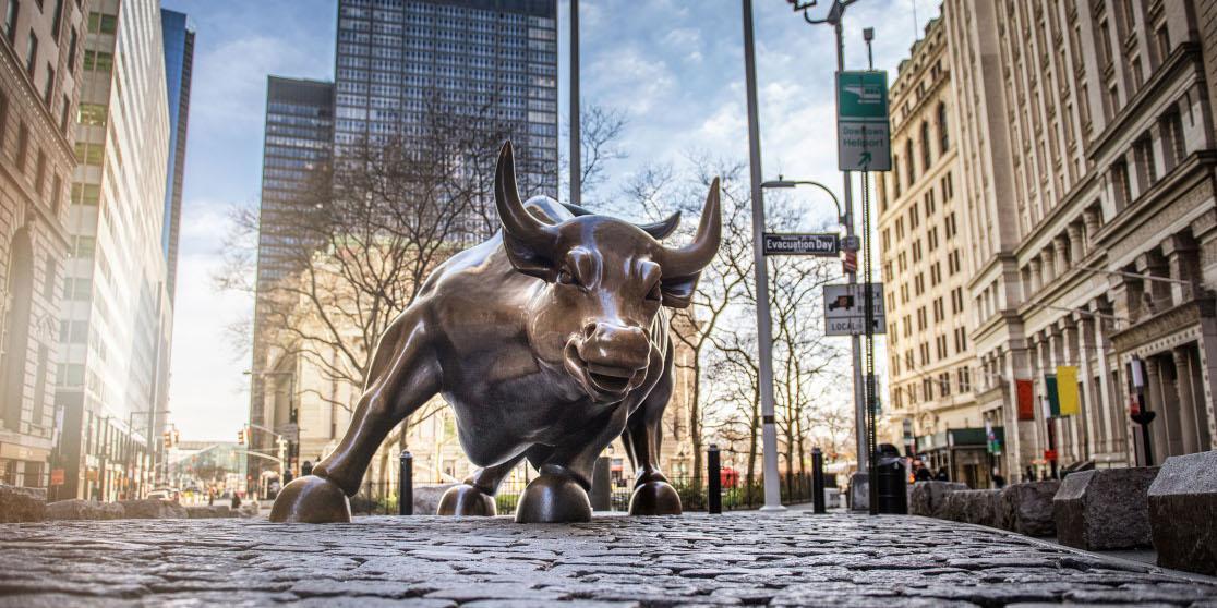 A photo of the Wall Street bull statue from a low perspective on a sunny day.