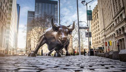 A photo of the Wall Street bull statue from a low perspective on a sunny day.